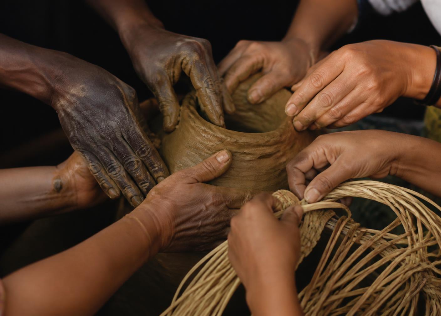 Many hands co-crafting clay and woven fibre together